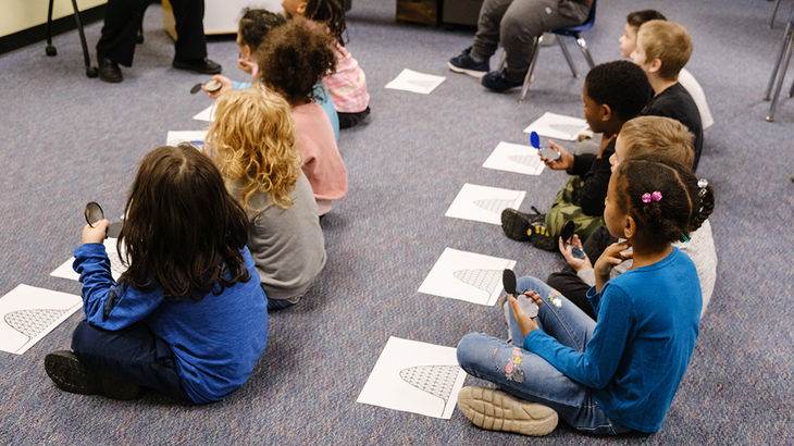 Kids sitting on floor doing a roller coaster worksheet