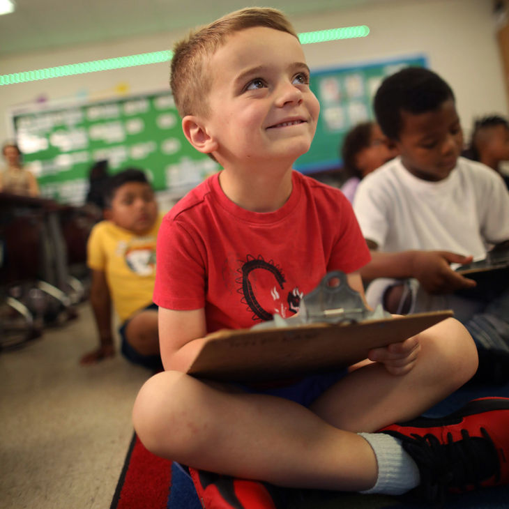 Smiling boy writing on a clipboard in class