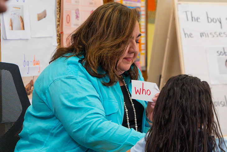 Teacher holding up card that says "who"