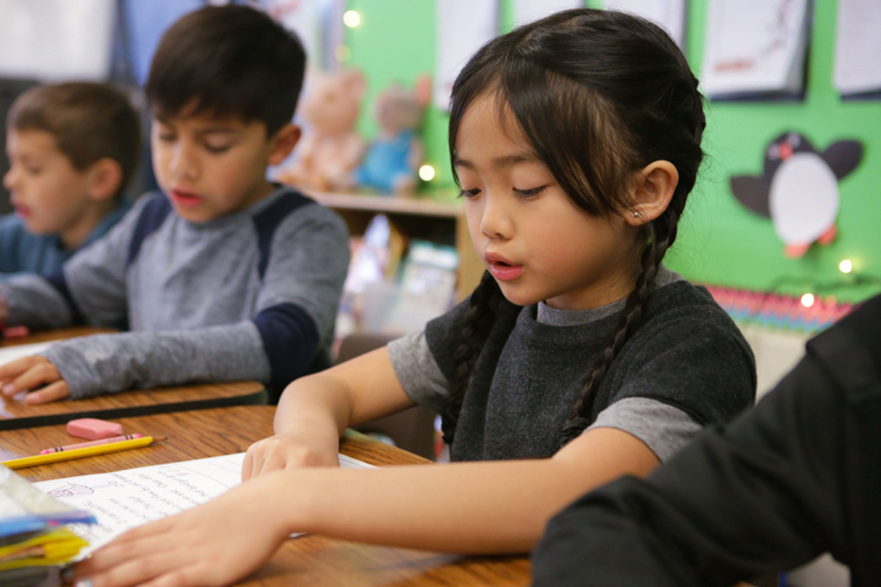 Young girl reading a worksheet aloud in class