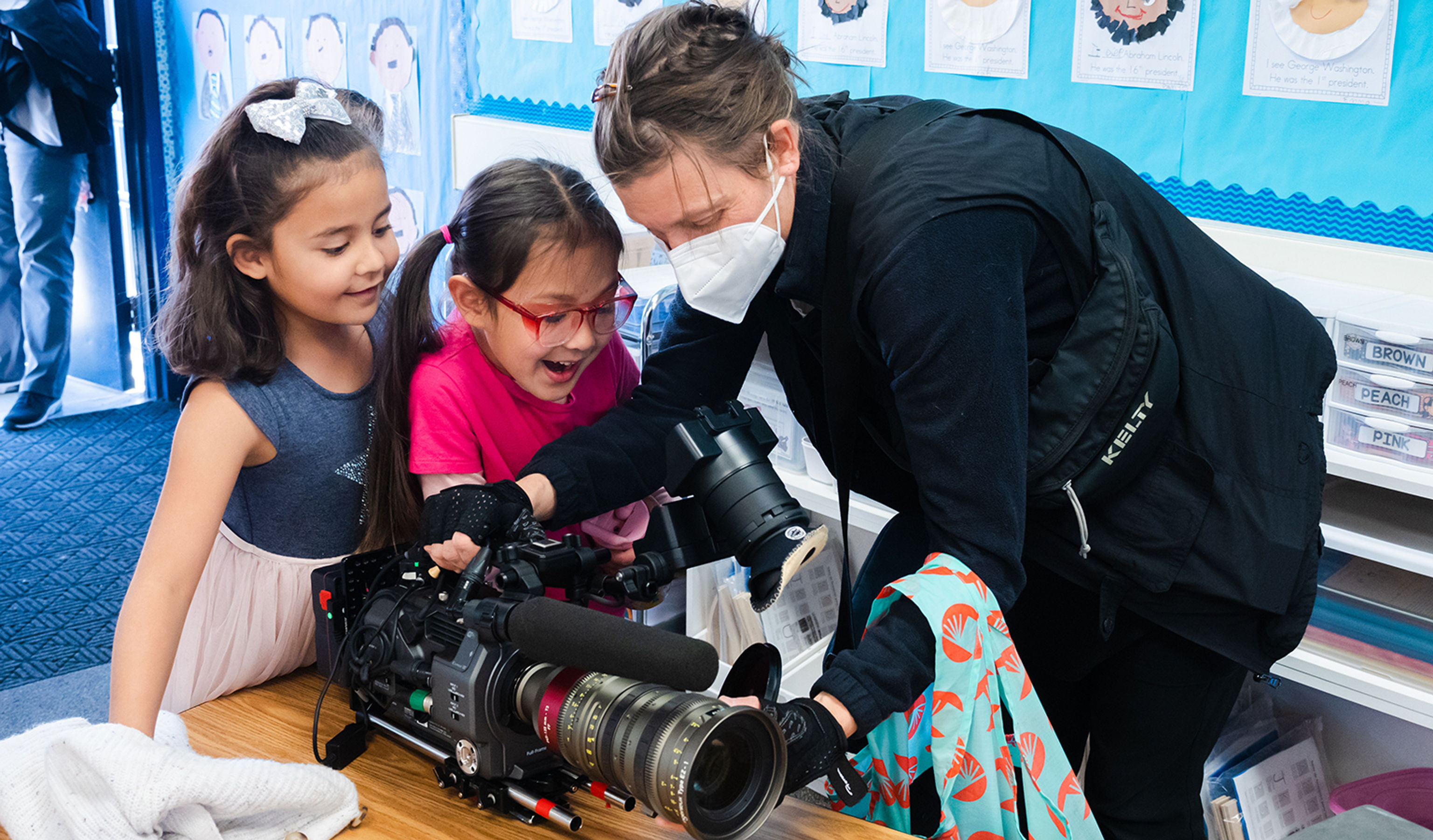 Young girls looking at a camerawoman's camera.