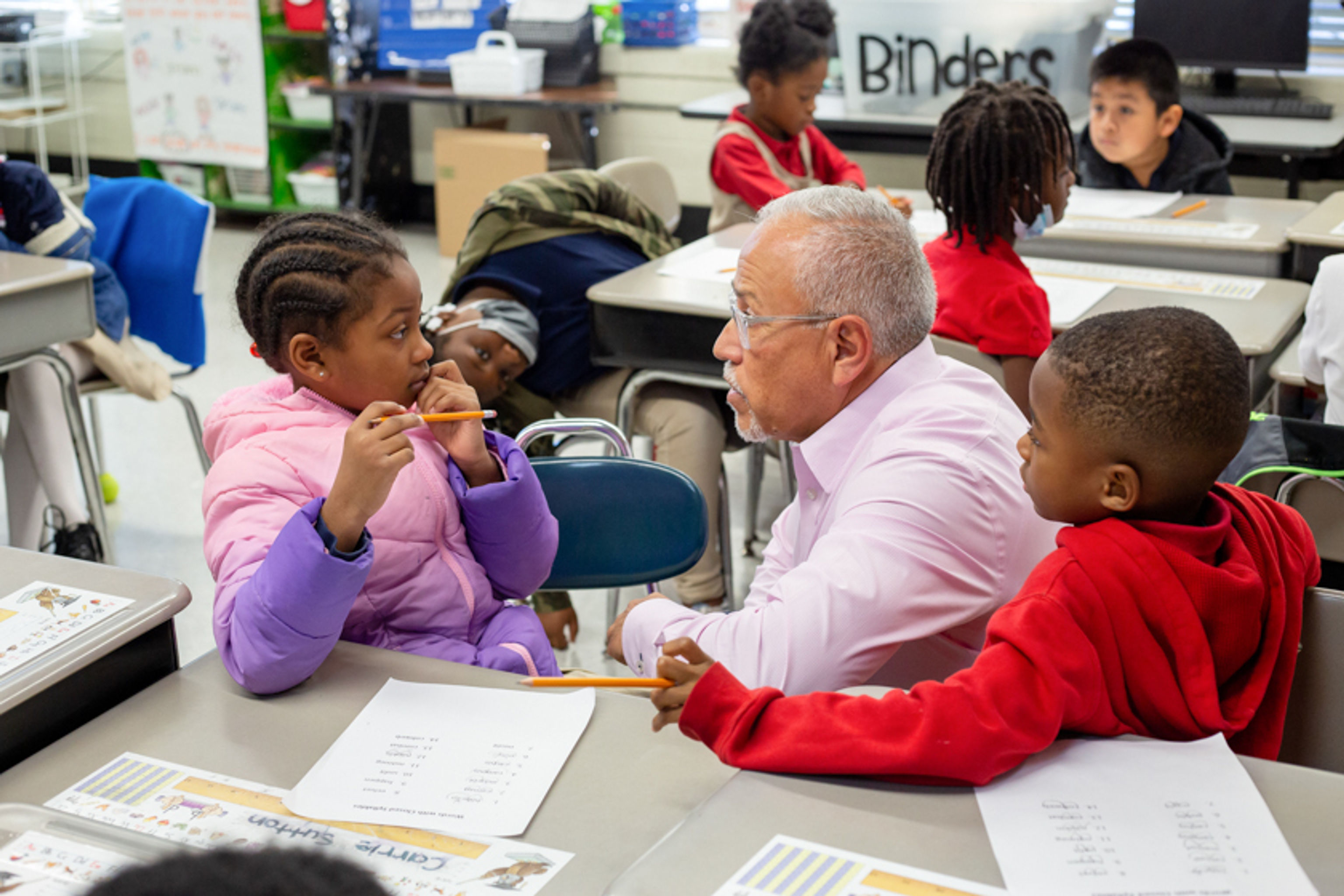 Teacher working with two students at their desks