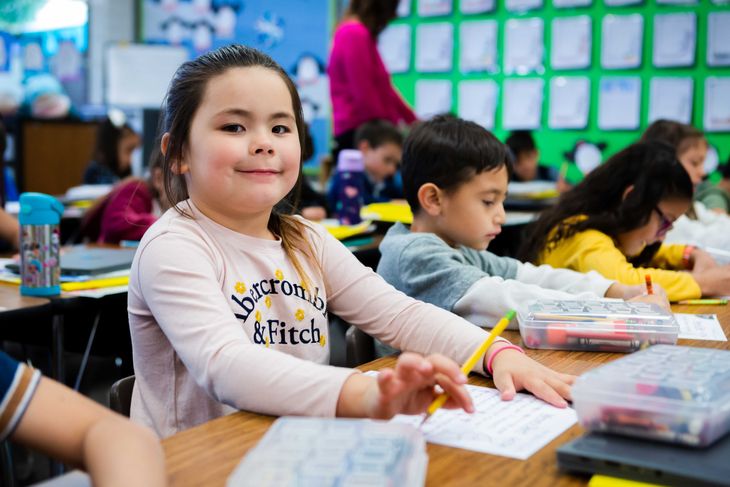 A young girl holds a pencil.