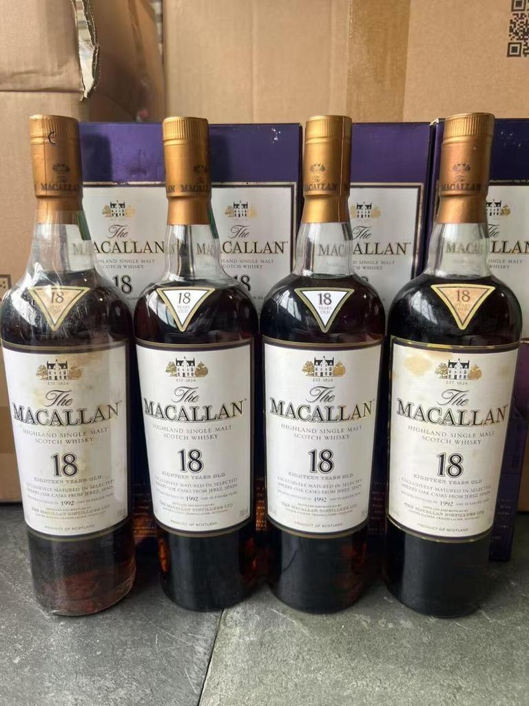 四瓶 Macallan 18 年直立排列，金色瓶帽、瓶頸與後方盒裝可見