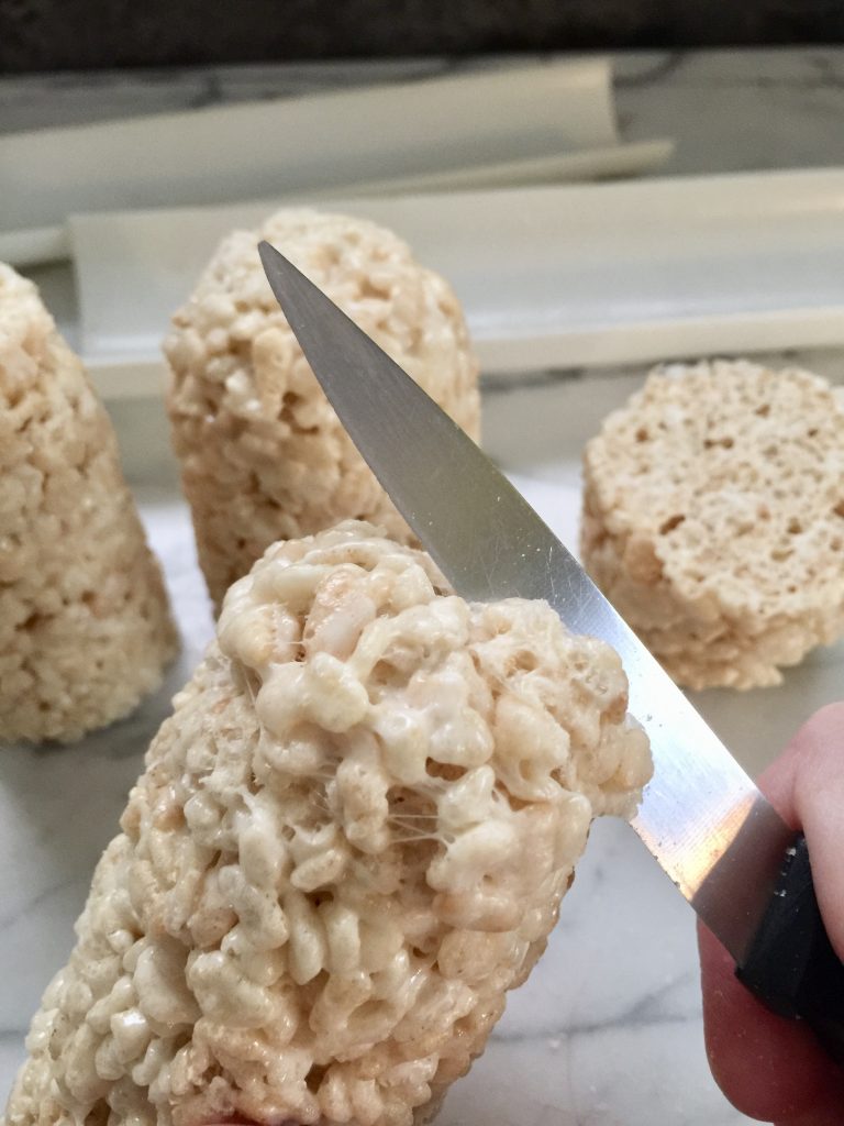 Rice Krispie treats rolled into a log And the tops being trimmed to round off for minion heads