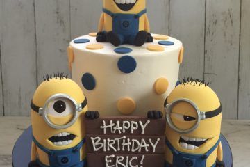Three minions on and around a cake with polka dots