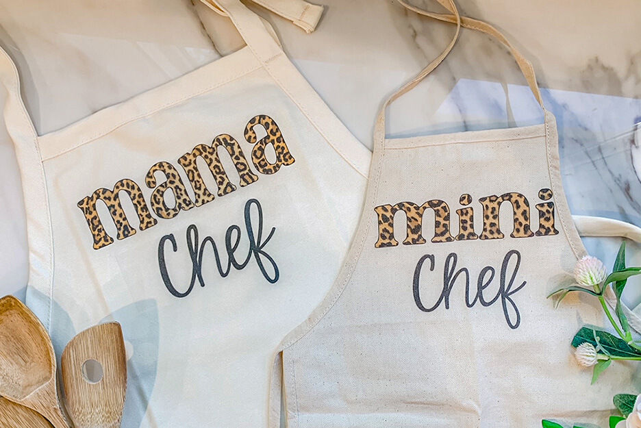 Wendy & Wander imprimió estos dos delantales blancos con las palabras “mama chef” y “mini chef” usando su impresora directo-a-prenda (DTG) VersaSTUDIO® BT-12 de Roland DG.