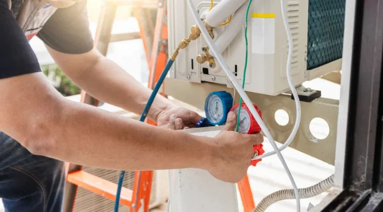 Technician repairing an air conditioner unit in New Delhi workshop.