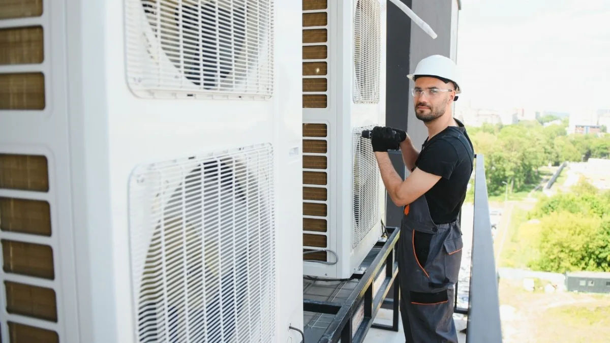 Technician repairing an air conditioner unit in New Delhi workshop.