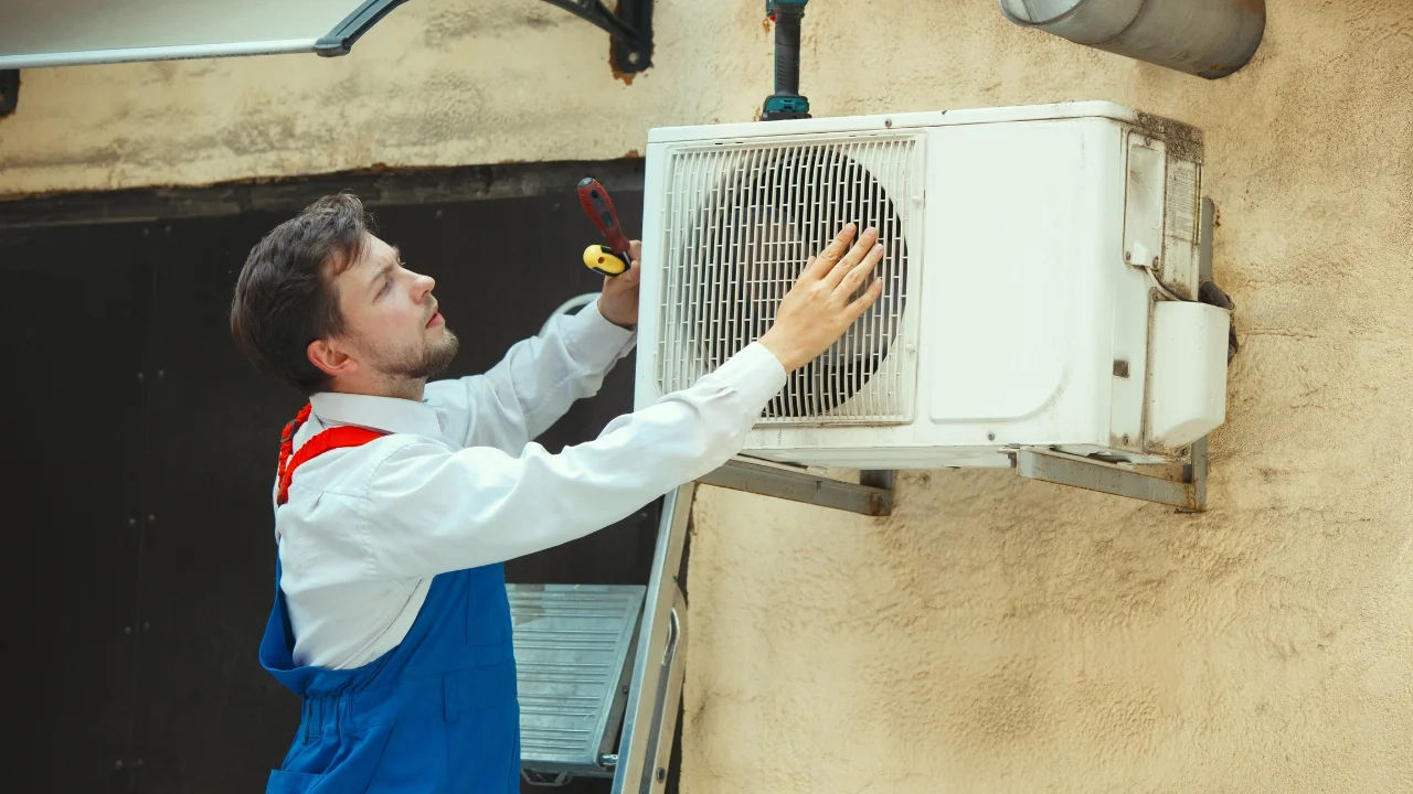 Technician repairing an air conditioner unit in New Delhi workshop.