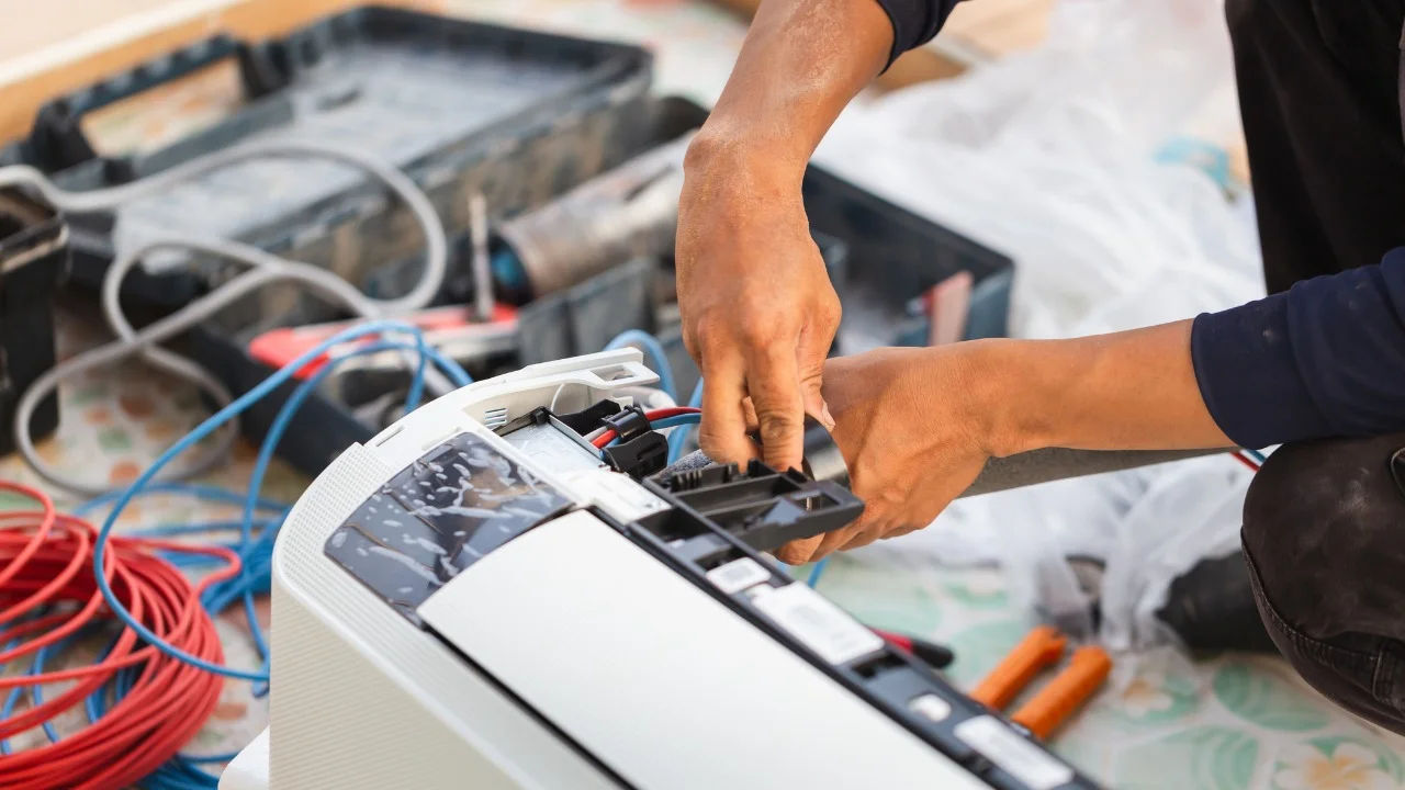 A technician skillfully repairing an outdoor air conditioning unit mounted on a building wall.