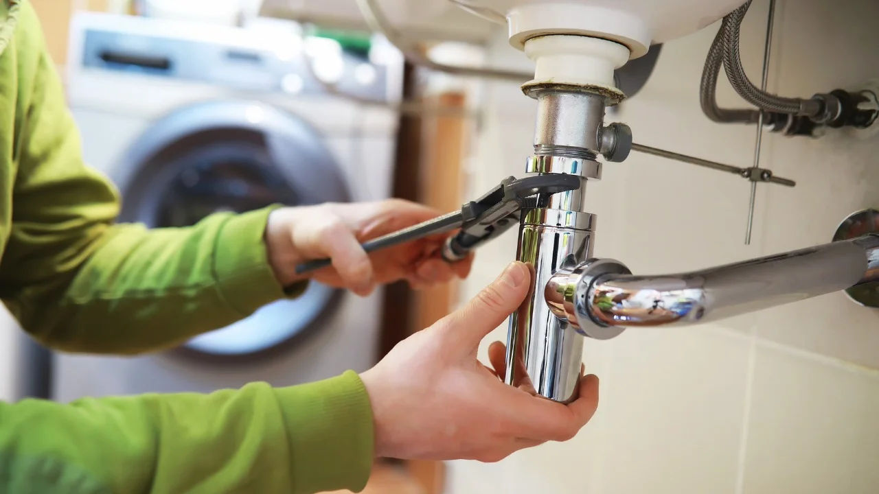Close-up of a plumber installing a radiator pipe using specialized tools.