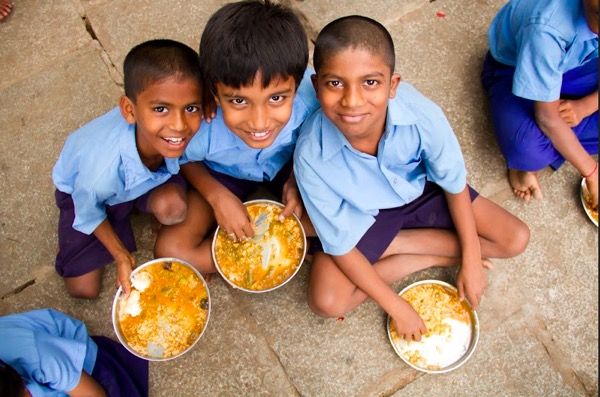 A group of children are sitting on the ground eating food