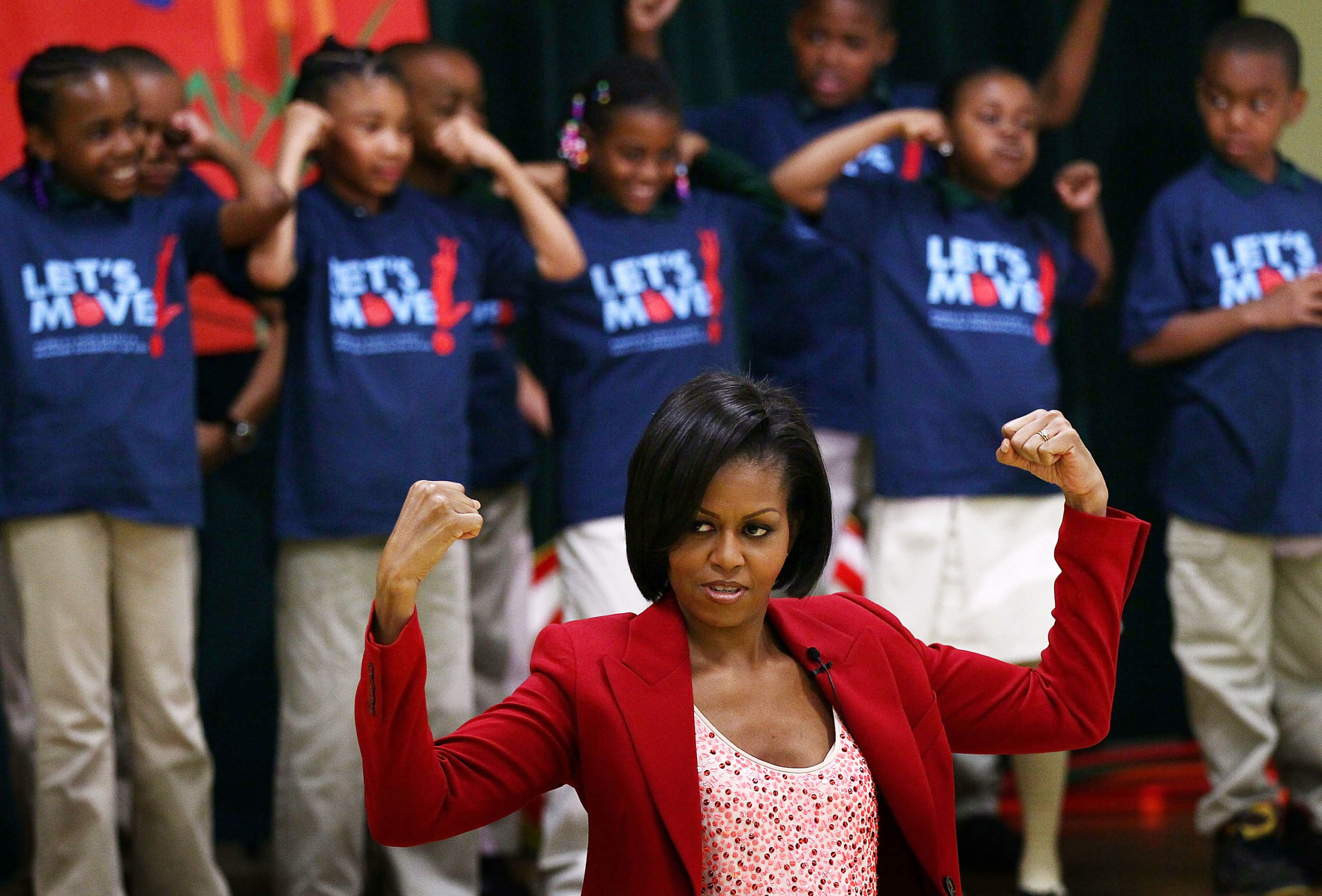 First lady michelle obama holds up a fist in front of a group of children