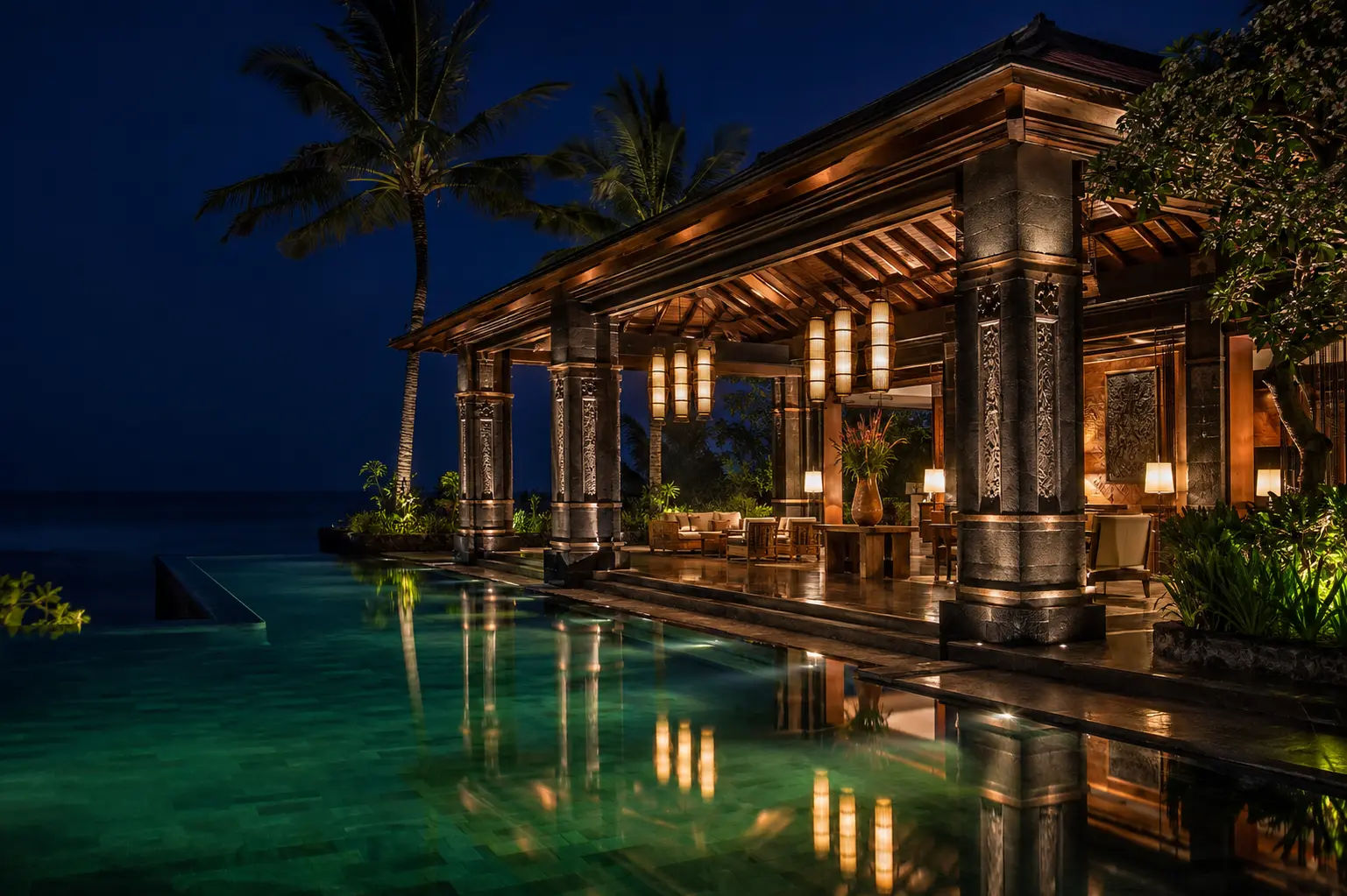 Paviliun hotel tropis dengan kolam berwarna emerald pada malam hari