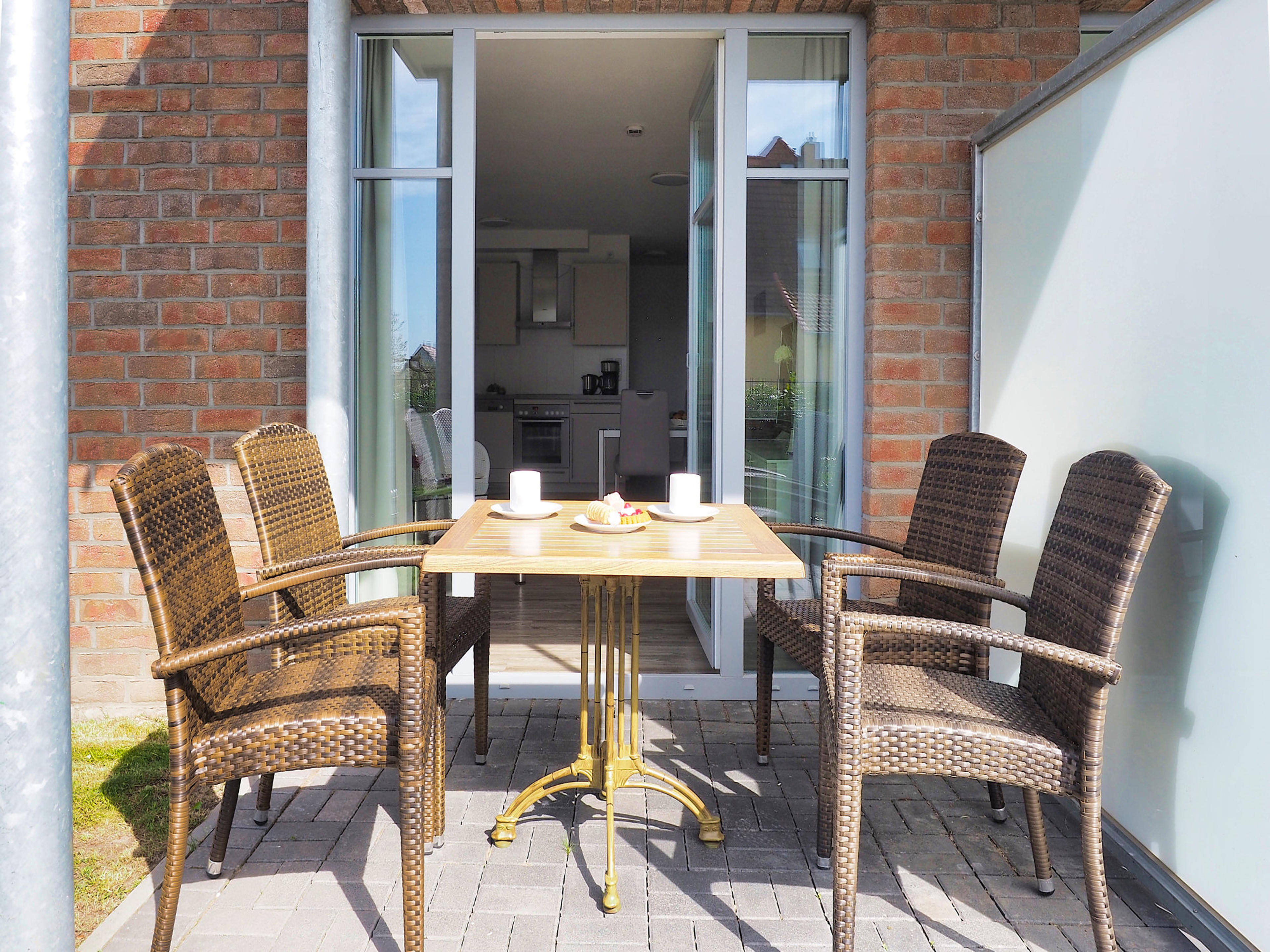 sonnige Terrasse mit Tisch und vier Stühlen