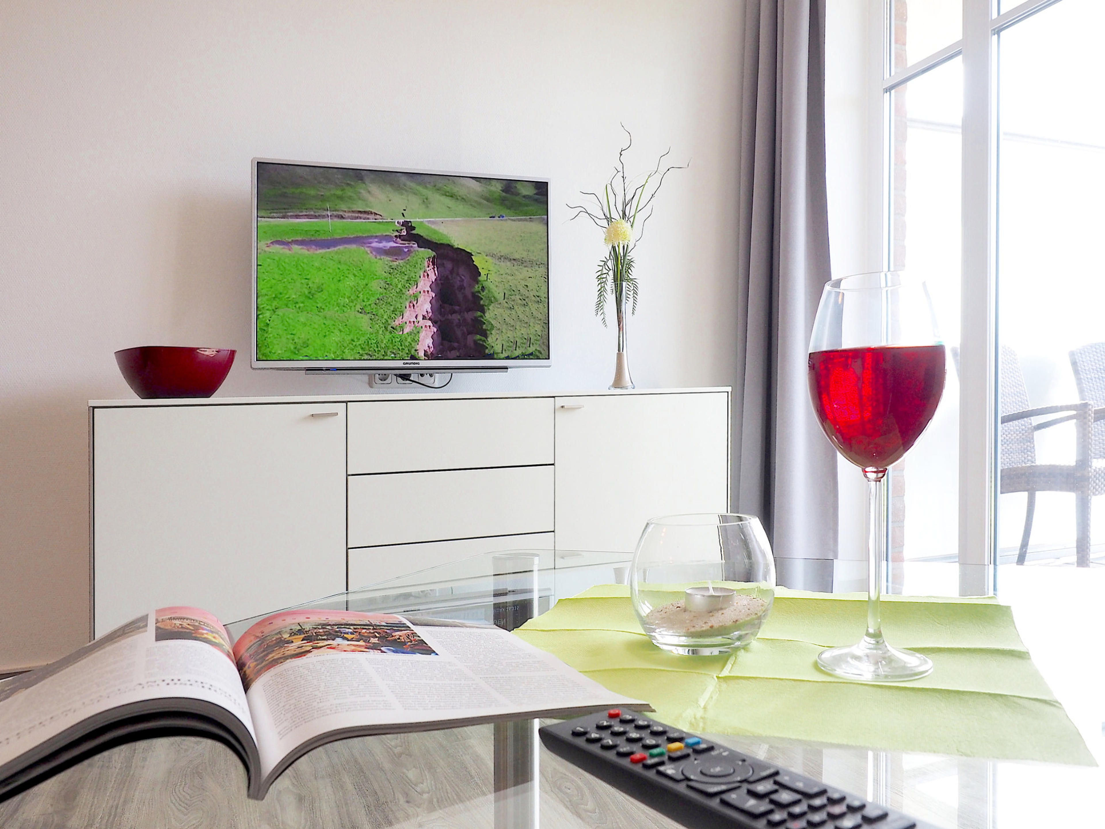 Wohnzimmer Sideboard mit Flatscreen-TV, im Vordergrund Glastisch