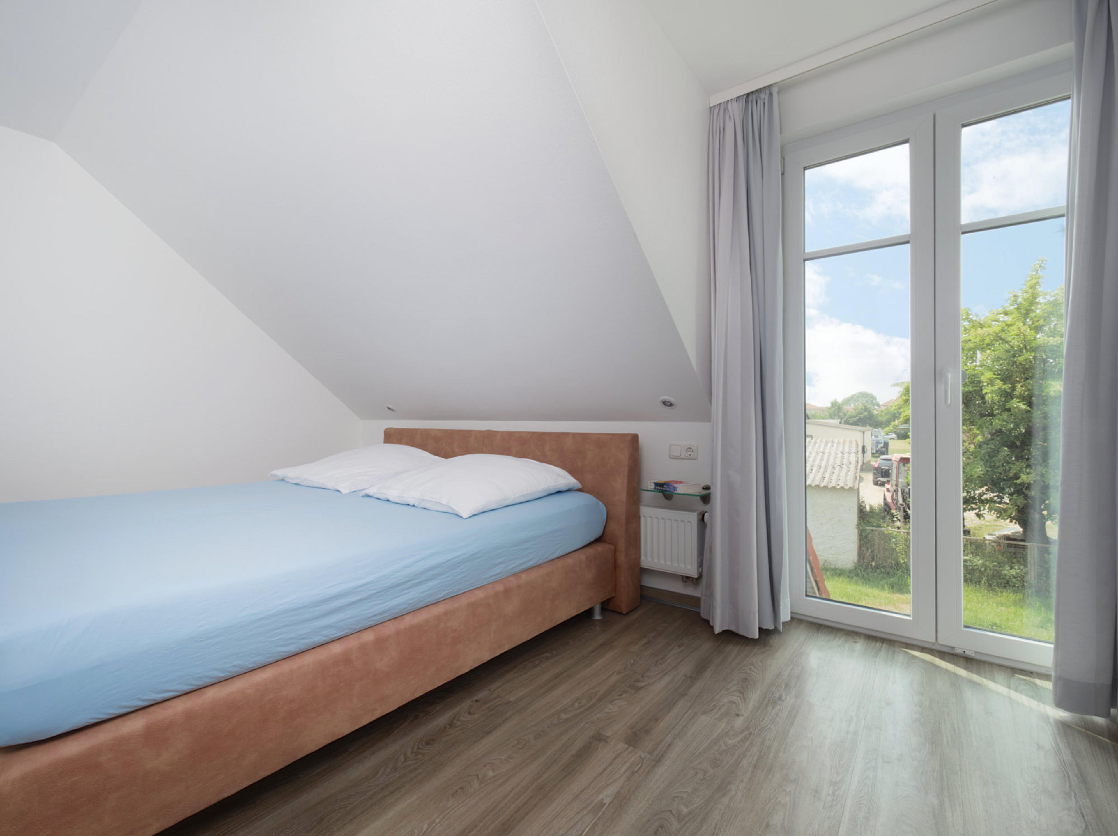 Meeresbrise, Ferienwohnung 07, zweites Schlafzimmer mit großem Doppelbett und Blick zu einem bodentiefen Fenster