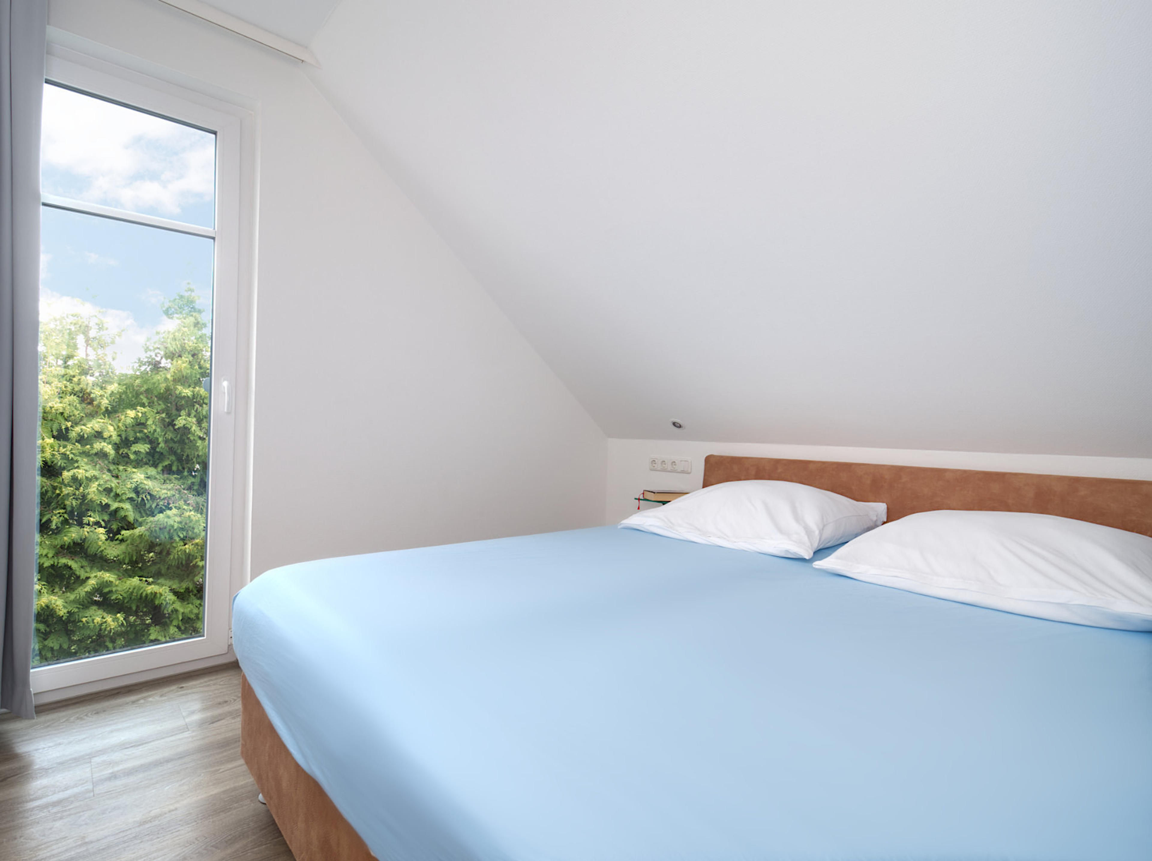 Meeresbrise, Ferienwohnung 08, Schlafzimmer mit großem Doppelbett und Blick zum bodentiefen Fenster