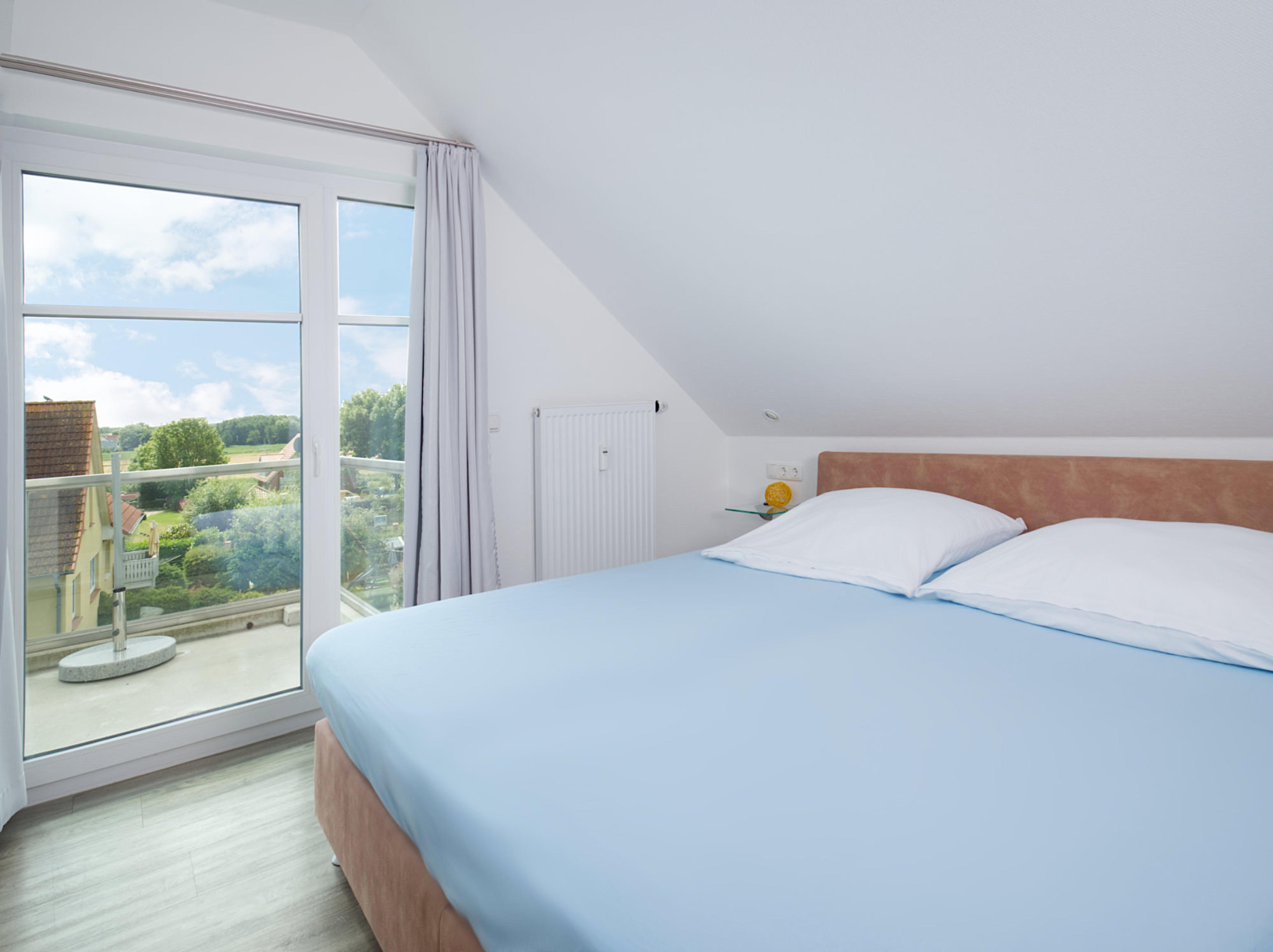 Meeresbrise, Ferienwohnung 09, Schlafzimmer mit großem Doppelbett und Blick zum bodentiefen Fenster