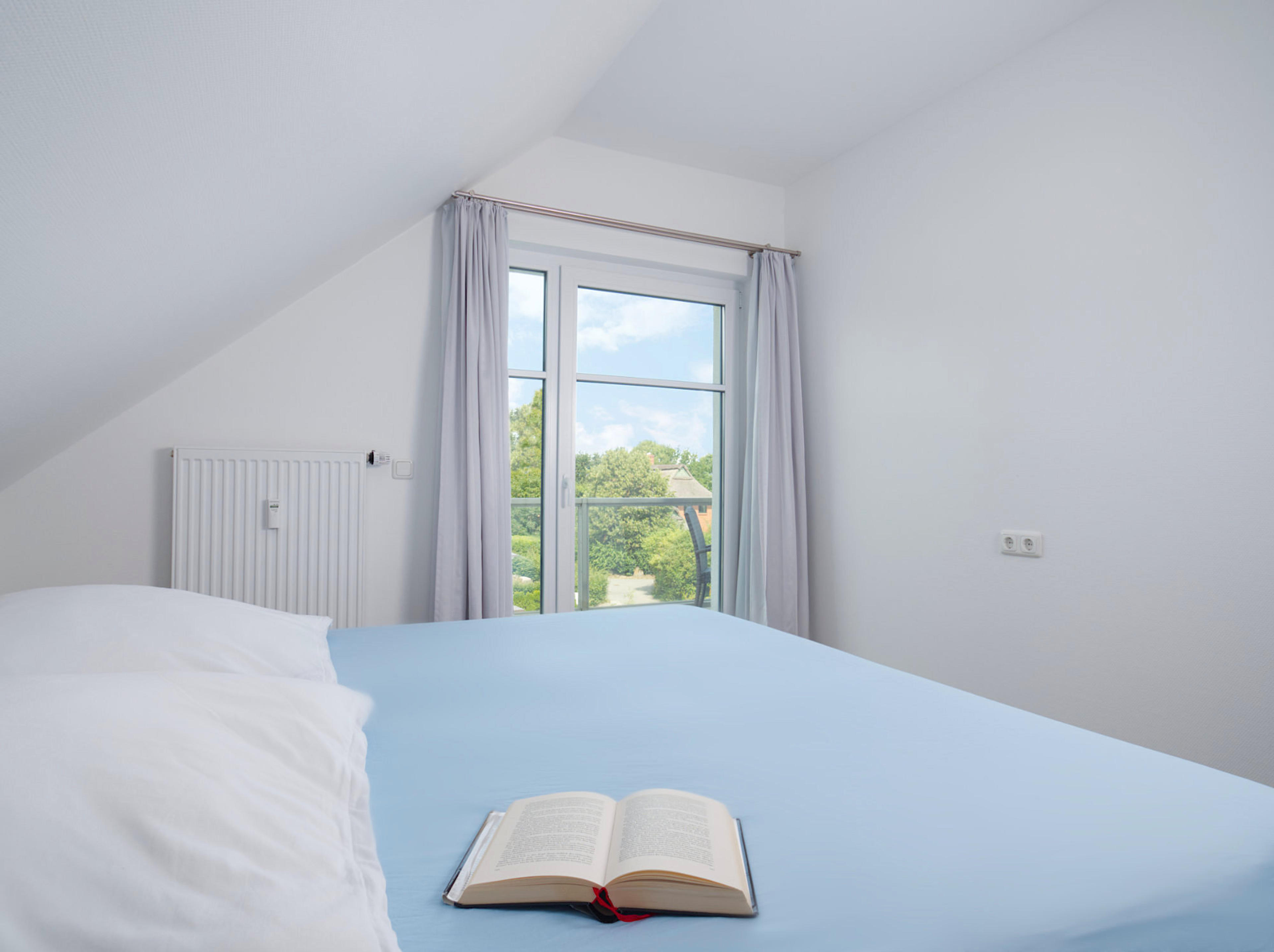 Meeresbrise, Ferienwohnung 10, Schlafzimmer mit großem Doppelbett und Blick zum bodentiefen Fenster