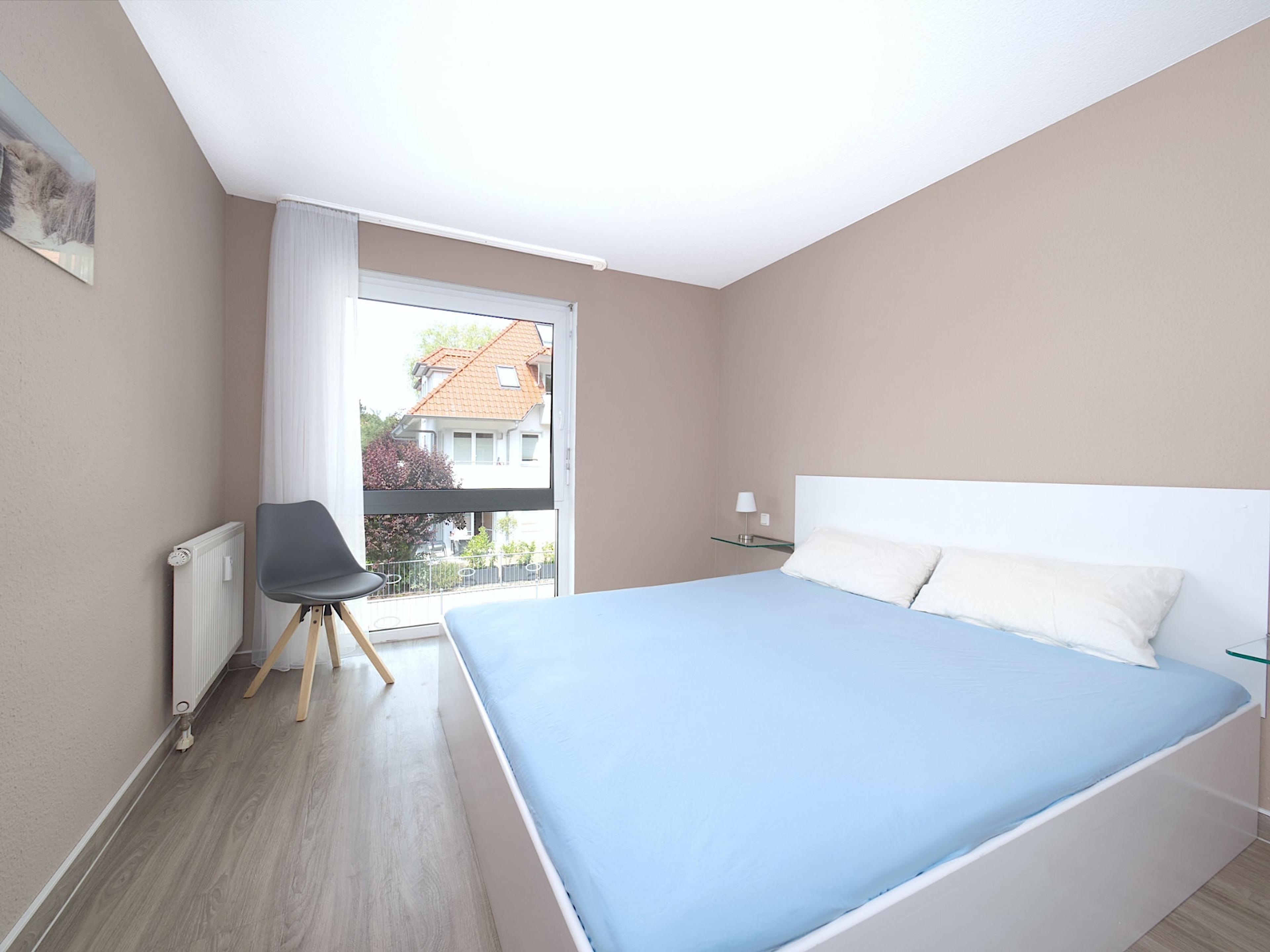 Residenz am Park, Ferienwohnung 10, Schlafzimmer mit großem Doppelbett und bodentiefen Fenstern