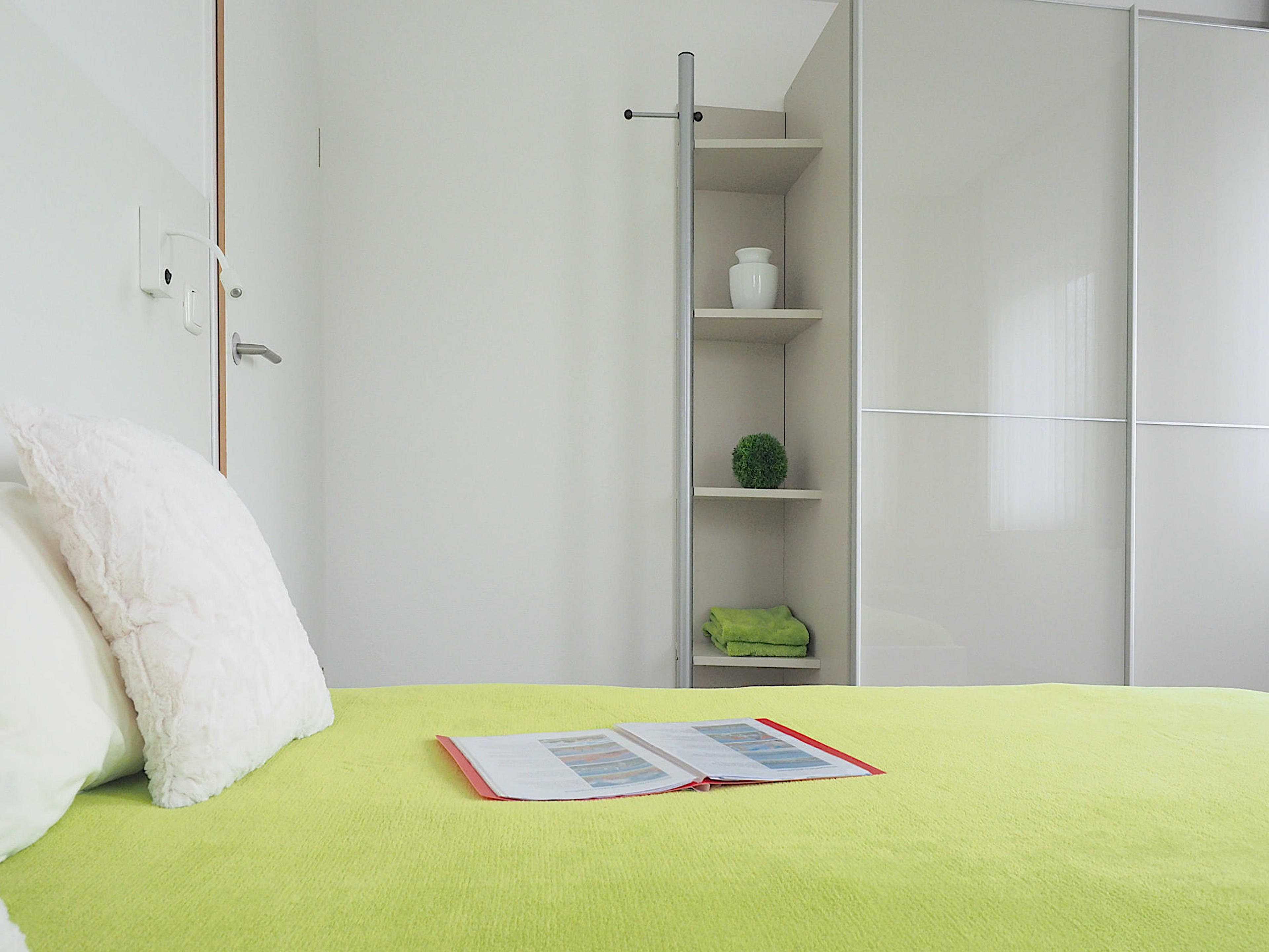 Zweites Schlafzimmer mit Doppelbett, rechts davon ein großer Kleiderschrank mit Regalteil
