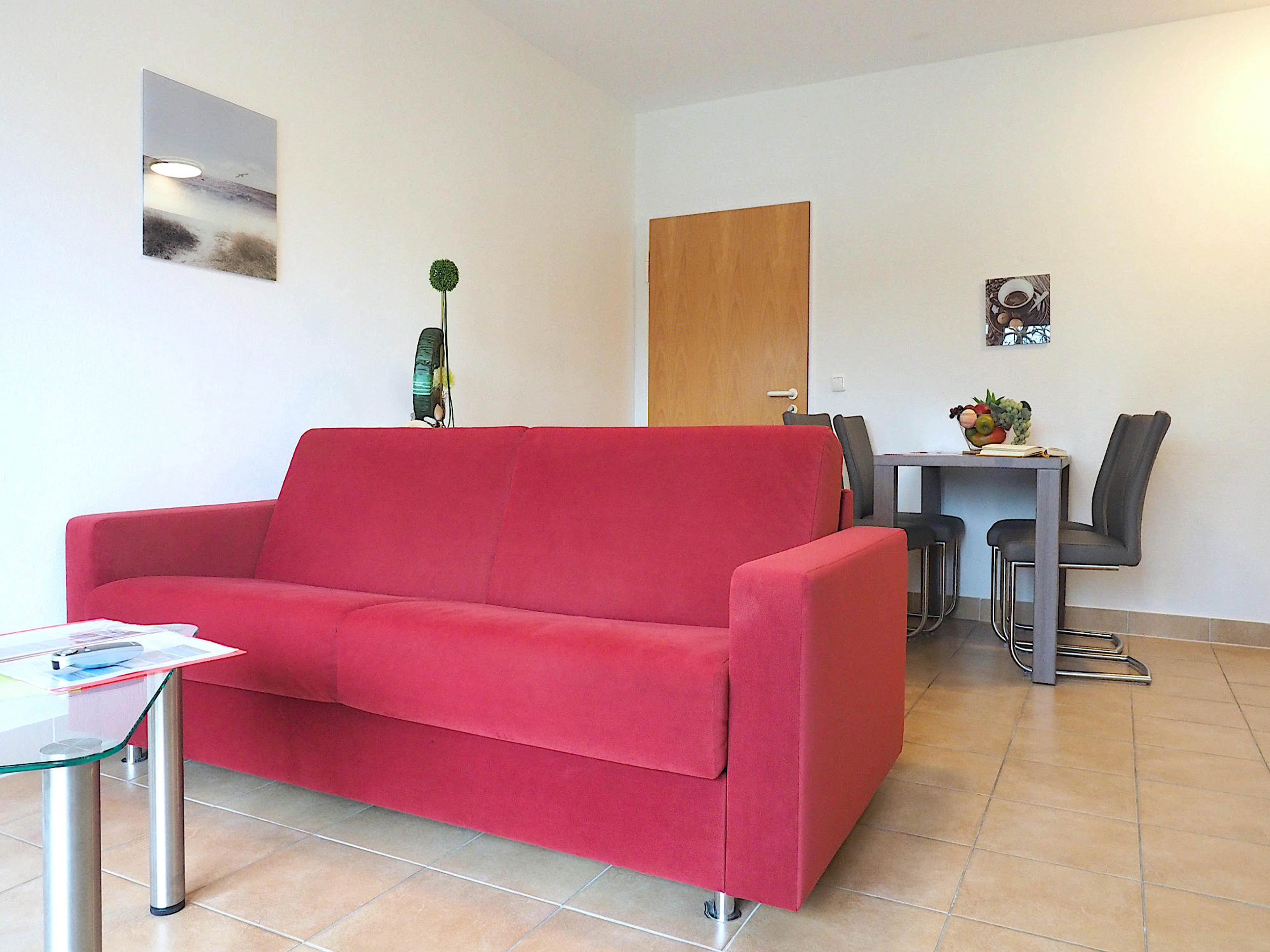 Wohnzimmer mit Couch, im Hintergrund ein Esstisch mit Stühlen
