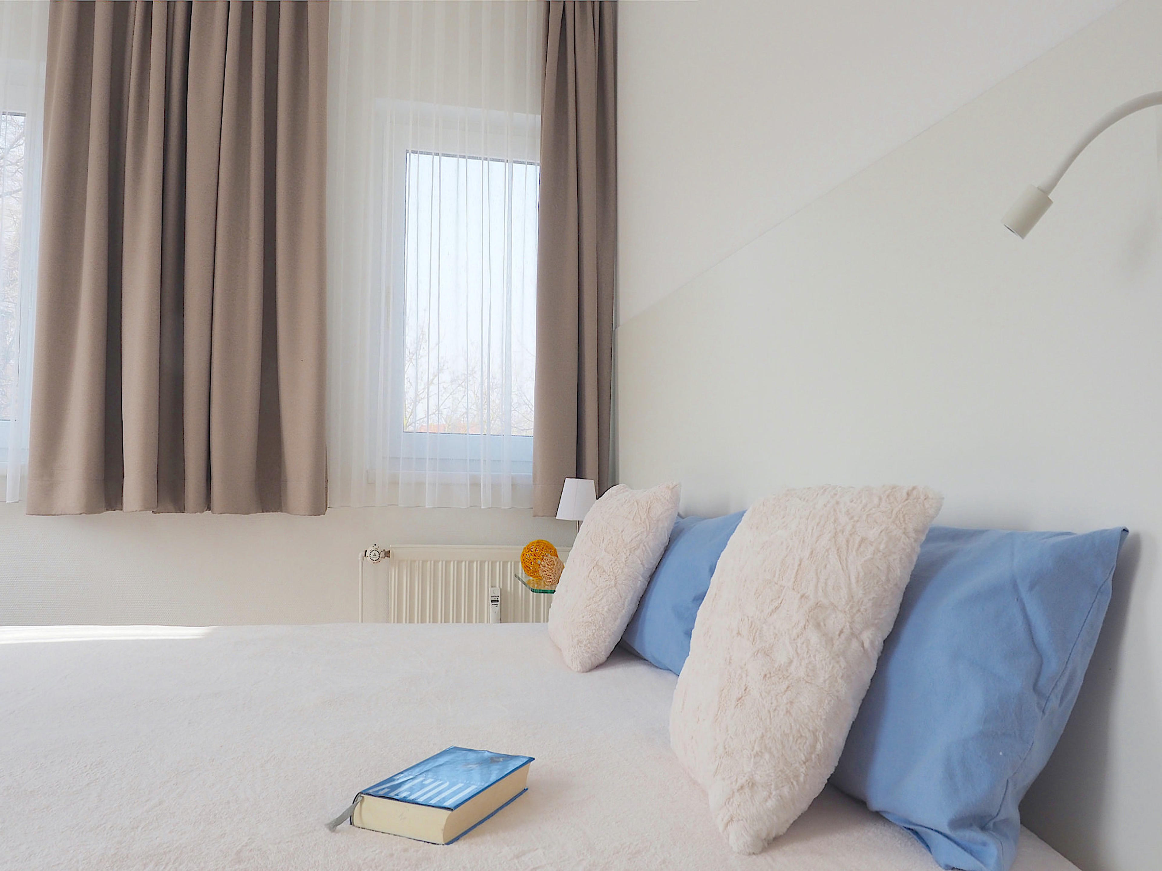 Zweites Schlafzimmer mit Doppelbett, hinter dem Kopfende ein breites Fenster
