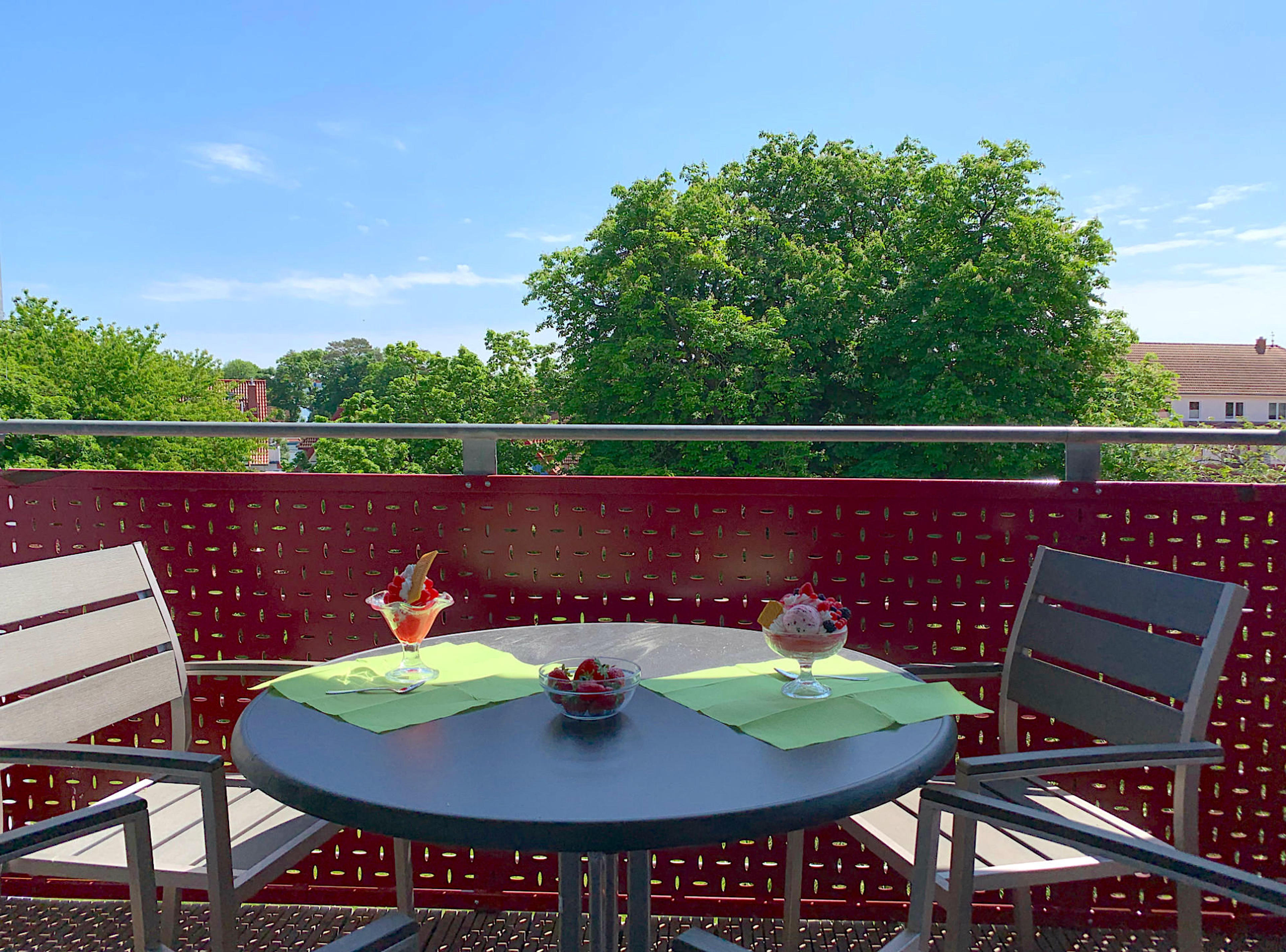 Balkon mit Tisch und Stühlen und Blick ins Grüne