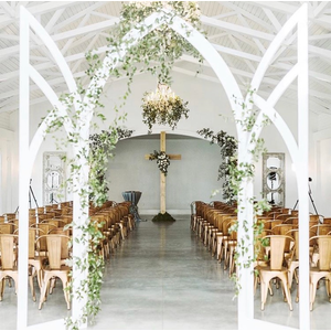 white arch backdrop with ivy with cross in the background 