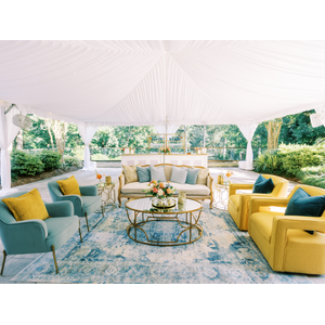 linen sofa with blue and yellow chairs outside under a tent at Umstead Hotel