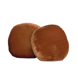 Circular, velvet pillow in a rust color