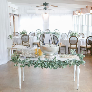 Classic white table with champagne flutes and greenery for wedding and bridal party.