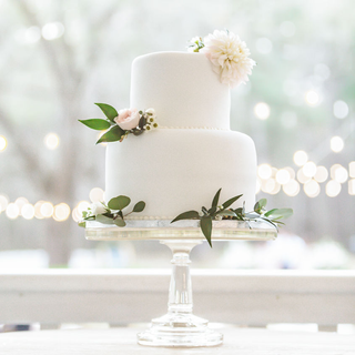 Pedestal glass cake stand with white two tier fondant cake.