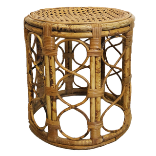 Vintage bronze gold round side table in a boho lounge set putdoors on grass that includes a boho rattan loveseat, a boho rattan floral shaped chairs, and boho rattan pouff floor pillows.