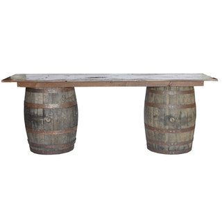 Midwest rustic wood rectangular barrel bar with crates and drink dispensers with glasses on the top of the bar. There are a few crates on the corner of the bar floor. 