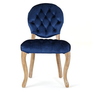Vintage velvet tufted royal blue chair with wood accents with a woman sitting on top of it. 