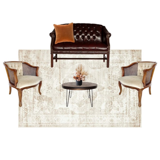 lounge set with leather brown sofa with a brown wood coffee table with vintage beige wood arm chairs on each side of the coffee table on a beige patterned rug.