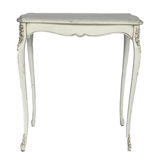 Vintage ivory beige rectangular accent table is inside of a room, infront of a glass panel door with white drapes hanging and wood flooring. On top of the table is a 3 tiered wedding cake with floral decor. A bride a groom smile as they cut into the cake 