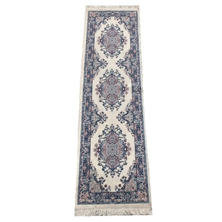 vintage blue rectangular runner rug down an aisle with a different runner under it and rows of chairs on either side of the runner. A couple stands at the end of it under a triangle arbor raising their arms. 