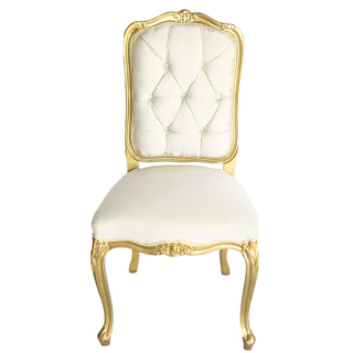 Vintage linen tufted ivory beige chair with gold accents in a lounge set that includes a gold and ivory beige vintage loveseat and a gold and glass round coffee table outdoors overlooking the ocean and city. 