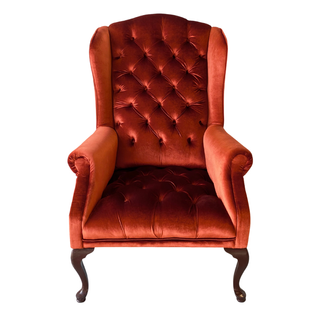 Vintage velvet tufted burnt orange terracota arm chair with wood legs in a lounge set with white loveseat, a cushioned wood bench and a gold round coffee table. 