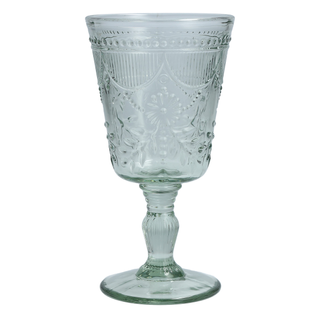 sage goblet glasses tableware on a linen table with tableware and florals surrounding it and warm lights blurred in the background. 