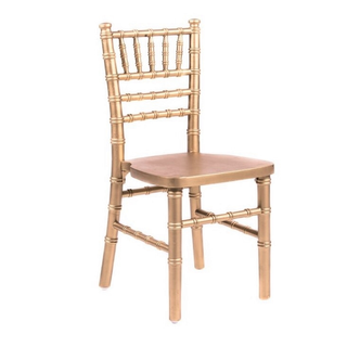 Kiddie gold chiavari child chairs with gold legs tucked into a linen table with gift bags on top of it. 