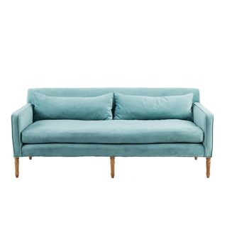 A dusty blue velvet sofa with carbed wood legs.