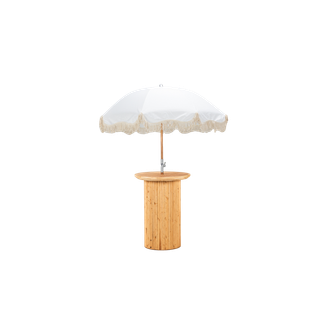 light wood cocktail table with a textured base paired with a white fringe umbrella 