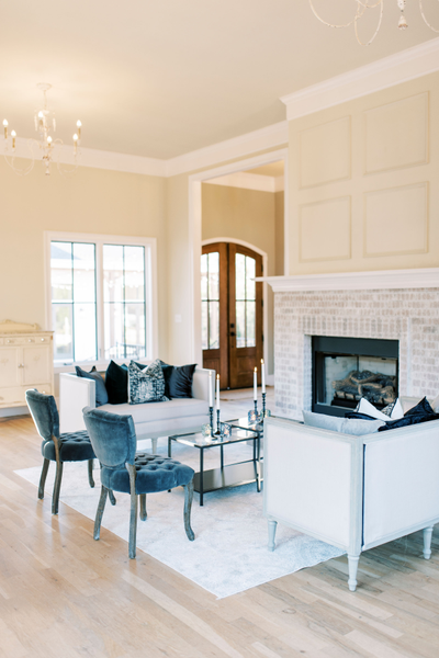 Two square linen settees with two dark gray chairs and black nesting tables 