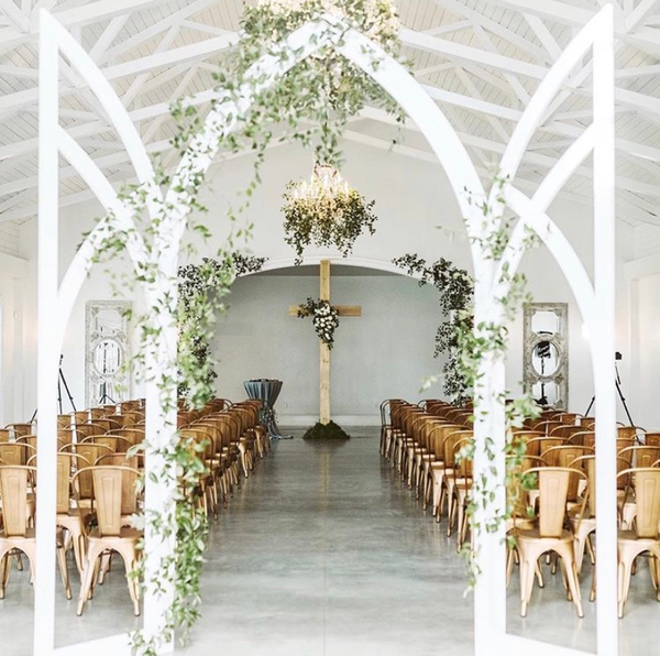 white arch backdrop with ivy with cross in the background 