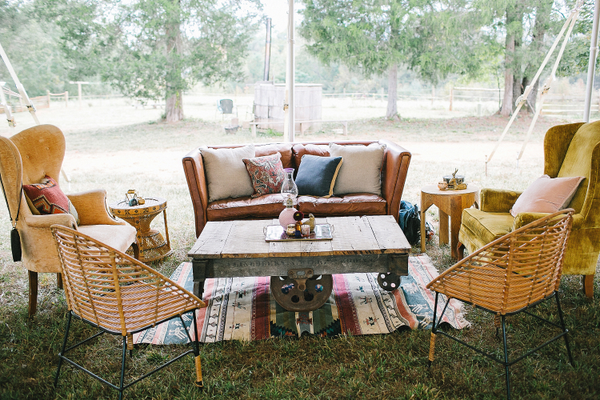 Vintage leather sofa with two vintage mustard chairs, two rattan chairs, and industrial cart table 